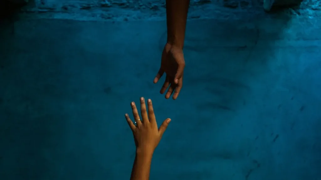 two hands reach towards each other underwater